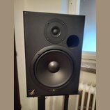 Černý studiový monitor v hranatém korpusu s dvěma reproduktory a bassreflexním otvorem. V levém dolním rohu je bílé logo s nápisem Event. Povrch je m…