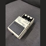 Bílý efekt pedál Boss Noise Suppressor NS-2 v kompaktním kovovém provedení s černým gumovým spínacím pedálem. Na horní části jsou čtyři bílé ovládací…