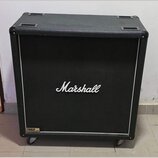 Černý kytarový reproduktorové box s texturovaným povrchem a bílým lemováním. Uprostřed přední mřížky je bílé logo Marshall a v levém dolním rohu štít…