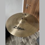 Zlatý kovový činel umístěný na stojanu. Na povrchu je černý nápis Zildjian a v horní části logo A s textem MEDIUM CRASH 18" / 45 cm. Povrch vykazuje…