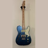 Modře lakovaná elektrická kytara s dutým korpusem a f-otvorem. Na hlavě hmatníku je nápis Squier a modelové označení Telecaster. Nástroj má světlý dř…