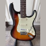 Elektrická kytara s trupem v barevném přechodu od černé přes hnědou k žluté a krčkem z tmavého dřeva. Má krémový pickguard, tři snímače s bílými kryt…