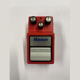 Červený efekt pedál s nápisem Maxon Compressor/Limiter. Horní část obsahuje tři černé ovládací knoflíky s kovovými vršekmi a popisky THRESHOLD, REDUC…