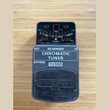 Šedý kytarový ladič s černým displejem a ovládacími prvky. Na zařízení jsou nápisy BEHRINGER, CHROMATIC TUNER a TU300, dále označení OUT, IN, BYPASS…