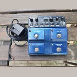 Modrý kytarový looper s kovovým povrchem a ovládacími prvky. Na horním panelu jsou nápisy JamMan, LOOP LEVEL, RHYTHM LEVEL, RECORD, PLAY, OVERDUB, MI…