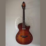 Akustická kytara s hnědým gradientním povrchem a vyřezanými otvory v těle místo klasického otvoru. Na hlavě hmatníku je bílý nápis Crafter. Nástroj j…