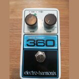 Bílý kytarový pedál s nápisy nano looper a 360 v modrém rámečku. V horní části jsou dva černé oválové knoflíky s popisky LEVEL a LOOP, nad nimi nápis…