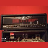 Černý kytarový kombozesilovač s kovovou mřížkou a logem Peavey v horní části. Na ovládacím panelu jsou nápisy ValveKing TUBE AMPLIFIER a VK 100. Pane…