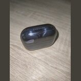 Černý nabíjecí box s průhledným víkem, uvnitř kterého jsou umístěna dvě bezdrátová sluchátka. Na horní části víka je bílý nápis SAMSUNG. Povrch průhl…