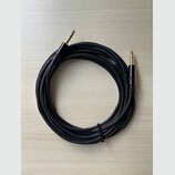 Černý audio kabel s pozlacenými 6,3mm jack konektory na obou koncích. Kabel je svinutý do kruhu a upevněný černým suchým zipem. Povrch kabelu i konek…