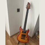Elektrická kytara s trupem v červeno-žlutém sunburst provedení a viditnou strukturou dřeva. Na hlavě hmatníku je bílý nápis FERNANDES. Nástroj má dva…