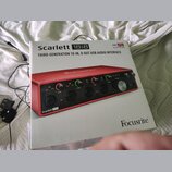 Fotografie znázorňuje bílou krabici s produktovou fotografií červeného audio rozhraní. Na krabici jsou nápisy Scarlett 18i8, THIRD-GENERATION 18-IN,…