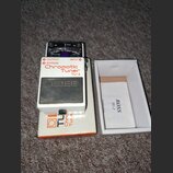 Bílý ladicí pedál s nápisy Chromatic Tuner a TU-2. Na horním panelu je analogový ukazatel s nápisy CHECK, GUITAR a CHROMATIC. Uprostřed je vyvýšené č…
