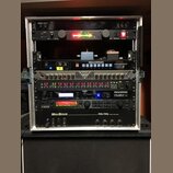 Stříbrný rackový kufřík s několika zařízeními. Obsahuje jednotky s nápisy KORG, The Rocket VM-100, ROCKTRON TriAxis, ROCKTRON HUSH a Mesa/Boogie Fift…