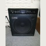 Černý basový kombo zesilovač s kovovou mřížkou přes reproduktor. Na přední straně je bílé logo Laney a nápis R68 v červeném čtverečku. Horní ovládací…