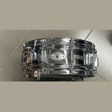 Chromovaný snare drum s kovovým korpusem. Na přednímstěně je oválný štítek s nápisy DYNA-SONIC, SERIAL NO. a CUSTOM BUILT. Nástroj vykazuje známky po…