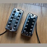 Dvě elektrické kytarové snímače typu humbucker s chromovaným krytem a černými cívkami. Na levém snímači je na spodní části černé plochy vyryt nápis U…