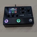 Černý efektový procesor Line 6 HX STOMP s kovovým povrchem v textuře glitter. Zařízení má digitální displej, čtyři ovládací knoflíky a tři nožní spín…