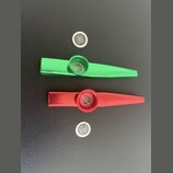 Dvě kovové píšťalky, jedna v zelené a druhá v červené barvě. Každá píšťalka má v horní části kulatý otvor a k nim jsou přiloženy dvě malé průhledné z…