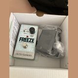 V bílém kartónovém boxu je efekt pedál stříbrné barvy s nápisy FREEZE, SOUND RETAINER a značkou electro-harmonix. Pedál má jeden černý ovládací knofl…