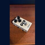 Bílý efekt pedál s nápisem OCD a značkou Fulltone Built in the USA. Na horní straně jsou tři černé ovládací knoflíky a jeden stomečový spínač. Na bok…