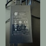 Černý plastový síťový adaptér s nápisem SWITCHING POWER SUPPLY a AUDIO/VIDEO POWER SUPPLY. Na štítku je uveden model S024AMP1200200, vstup INPUT 100-…