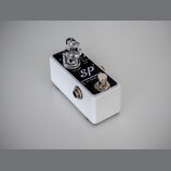 Bílý efekt pedál s černým horním panelem. Na panelu je nápis Sp compressor BY XOTIC, ovládací knoflík VOLUME a průhledný plastový knoflík. V dolní čá…