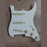 Bílá plastová pickguard pro elektrickou kytaru s třemi krky pro snímače typu single-coil. Na plastu jsou tři kroužky s nápisy VOLUME, TONE a TONE v b…