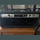 Černý rackový kufřík, v němž je osazen stříbrný zvukový interface. Na zařízení jsou nápisy apollo, UA UNIVERSAL AUDIO a logo 32 QUAD. Přední panel ob…