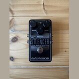 Černý efekt pedál s nápisy THE SILENCER a noise gate/effects loop. Na horní straně jsou dva ovládací knoflíky s popisky RELEASE a THRESH. V dolní čás…