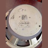 Záběr na zadní stranu magnetu reproduktoru s kovovým rámem. Na povrchu magnetu je černý nápis TONSIL, model GDN 25/91 a údaje 60 W 8Ω, pod nimi nápis…
