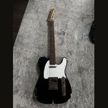 Černá elektrická kytara typu Telecaster s bílým pickguardem a hnědým hmatníkem. Na hlavě je viditelné logo Squier. Instrument vykazuje výrazné opotře…