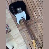 Černá elektrická kytara typu Telecaster s bílým pickguardem a hnědým hmatníkem. Na hlavě kytary je nápis "Spirit" a pod ním "TELECASTER". Povrch čern…