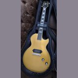Zlatá elektrická kytara s jedním humbuckerem v pozici kobylky, umístěná v černém obalu. Na hlavě nástroje je bílé logo Epiphone a nápis Les Paul Spec…