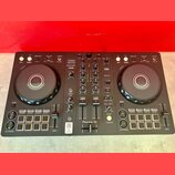 Černý DJ kontrolér s dvěma jog-koly a centrálním mixážním sekcí. Na přístroji jsou nápisy PERFORMANCE DJ CONTROLLER, DDJ-FLX4, rekordbox a serato, v…