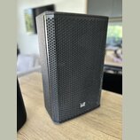 Černý reproduktor s kovovou mřížkou včelí struktury. V pravém dolním rohu je bílé logo LD Systems. Povrch skříně má jemnou texturu a vypadá být v dob…