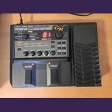 Černý kytarový syntetizátor Roland GR-20. Na předním panelu jsou vidět nápisy Roland, GUITAR SYNTHESIZER a GR-20 s červeným digitálním displejem zobr…