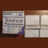Krabice a čtyři kusy recordable MiniDisc disků značky SONY, model bianca. Na krabici je nápis 80, 10 pack a seznam barev: Marshmallow Peach, Marshmal…