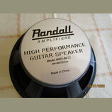Kruhový kytarový reproduktor s černým rámem a stříbrnou středovou krytkou. Na krytce je černý nápis Randall AMPLIFIERS a text HIGH PERFORMANCE GUITAR…
