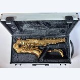 Zlatý saxofon v hliníkovém kufru s černým polstrováním. Nástroj je umístěn v originálním tvarovaném výlože a vedle něj leží samostatný krk s korkem.…