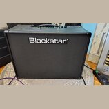 Černý kytarový kombozesilovač s texturovaným povrchem a černou přední maskou. Uprostřed je umístěno bílé logo Blackstar. Nástroj má v horní části čer…