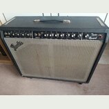 Černý kytarový kombo zesilovač s šedou textilní mřížkou. Na pravé straně je nápis Twin Reverb a na mřížce logo Fender. Horní ovládací panel obsahuje…