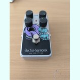 Stříbrný efekt pedál s černým předním panelem a čtyřmi černými ovládacími knoflíky. Na panelu je nápis Electro-Harmonix NEW YORK CITY, USA a grafický…