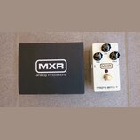 Bílá kytarový efekt pedál s nápisy MXR a micro amp +. Pedál má tři černé ovládací knoflíky s popisky GAIN, BASS a TREBLE, červenou kontrolku a stomeč…