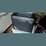 Černý kytarový kombozesilovač s textilní maskou reproduktoru. Na předním panelu je nápis LINE 6 a v dolní části texty 75 Watts, 400+ presets a 12" CE…