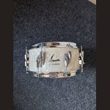 Bílá buben s perleťovým povrchem a chromovanými obručemi. Na horním obruči je nápis SONOR Vintage Superphonic a na korpusu se nachází logo Sonor s ná…