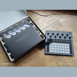 Šedý sampler Novation Circuit Rhythm s mřížkou bílých podsvícených padů a ovládacími knoflíky. V horní části je nápis CIRCUIT RHYTHM a v pravém horní…