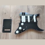 Černý plastový pickguard pro elektrickou kytaru s třemi bílými jednoznačkovými snímači. Na povrchu jsou tři bílé oválné knofíky s nápisy VOLUME, TONE…