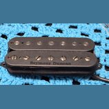 Černý humbucker snímač s plastovým krytem. Na spodní části je bílý nápis Seymour Duncan. Horní cívka má viditelné kovové pólové šrouby, spodní cívka…