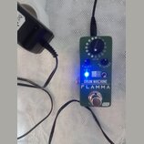 Zelený efekt pedál s nápisy DRUM MACHINE a FLAMMA. Obsahuje jeden ovládací knoflík s označením RHYTHM, dva modré přepínače LEVEL a EQ/SPEED, svítící…